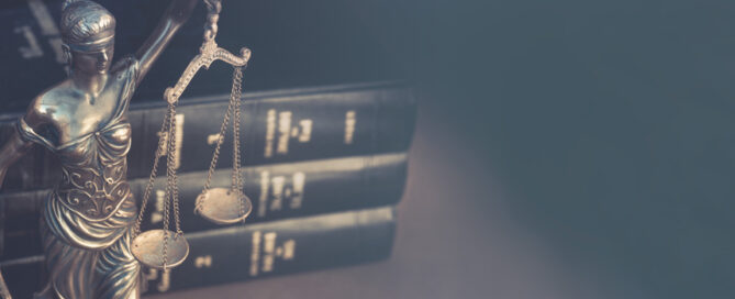 Lady justice holding scales in front of legal books
